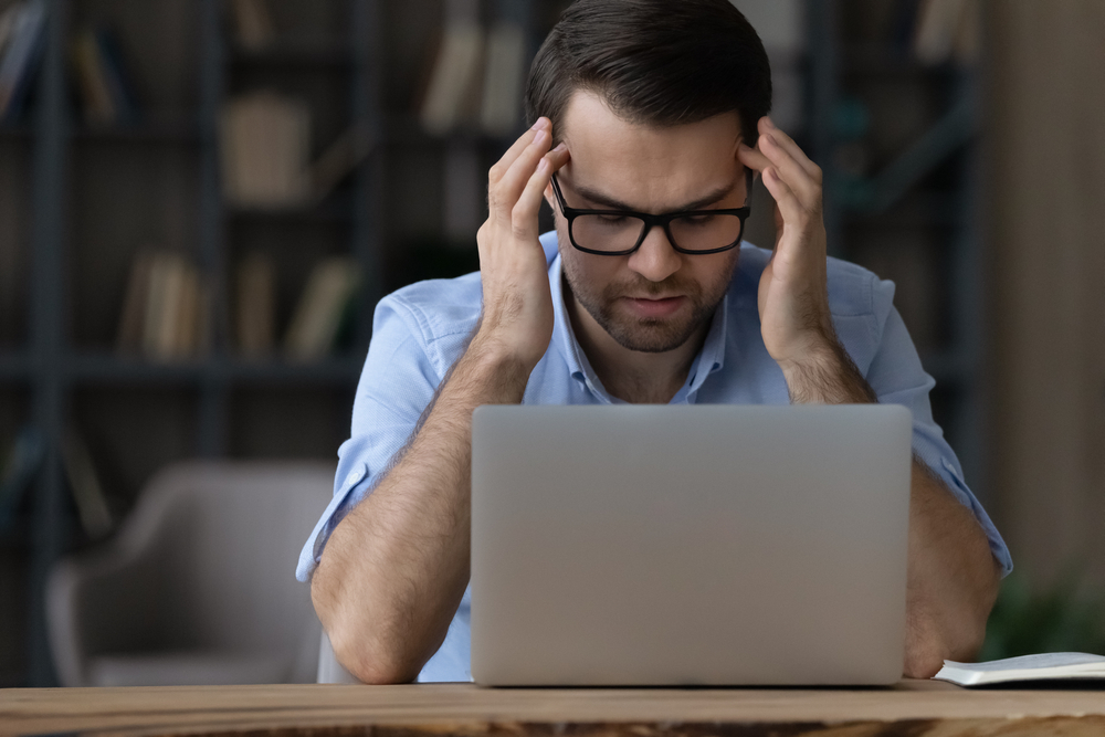 man with a headache in front of his computer