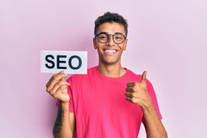 man smiling while holding a SEO sign